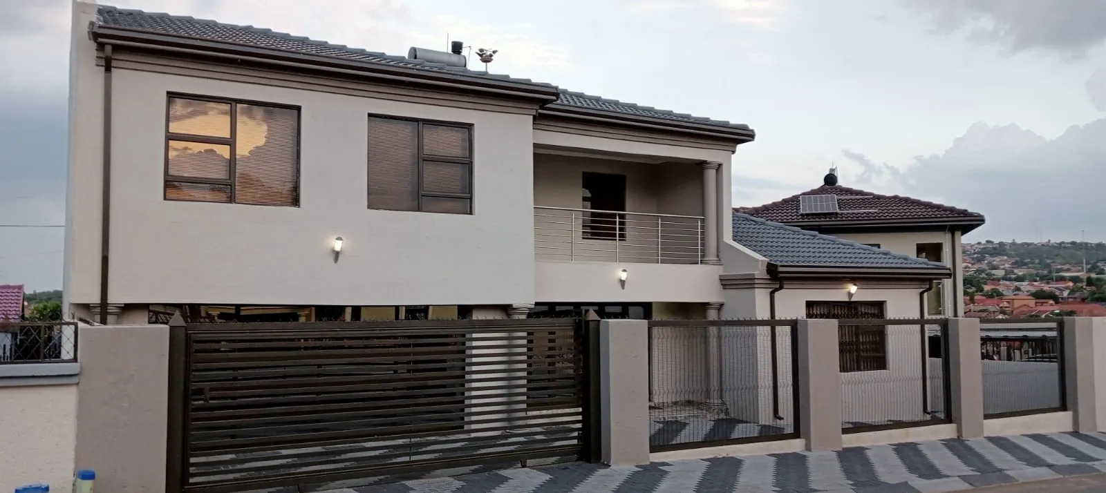 Double-storey home with bronze fascia boards and downpipes, galvanised gutters, bronze aluminium windows and a stainless steel balcony balustrade